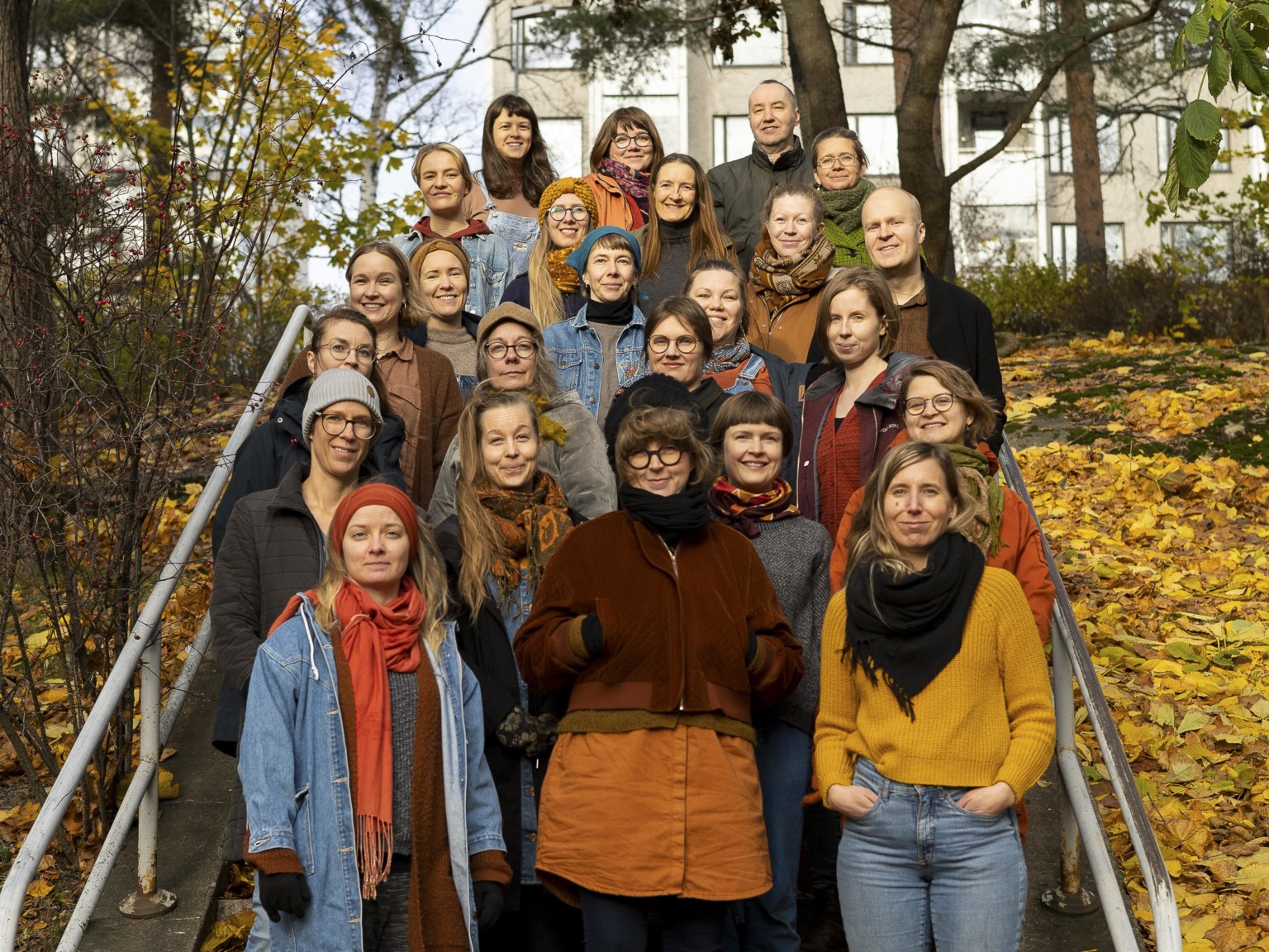 Members of Väki choir standing on the steps, surrounded by autumn nature.